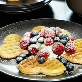 Knusprige IKEA Herzwaffeln mit frischen Himbeeren und Heidelbeeren, garniert mit Puderzucker – beliebtes Dessert im IKEA Restaurant