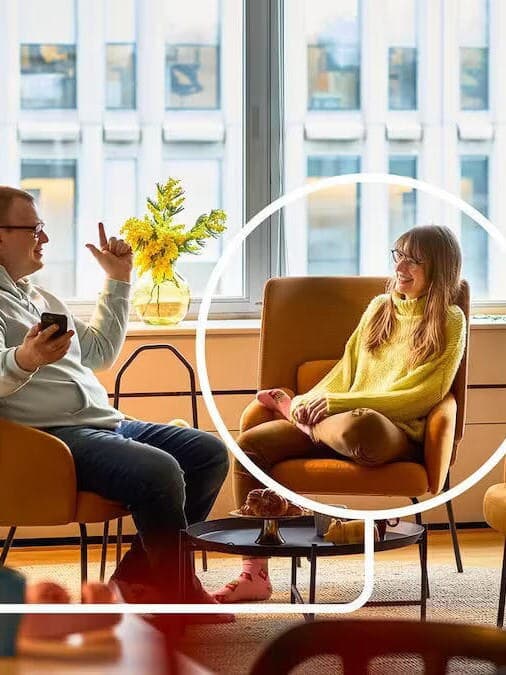 Kobieta i mężczyzna siedzący w żółtych fotelach i rozmawiający.