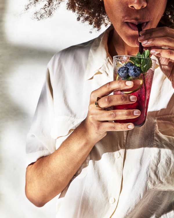 kobieta pijąca przez słomkę napoj w kolorze poczeki