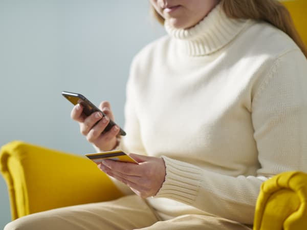 Kobieta przeglądająca stronę internetową IKEA na swoim smartfonie.