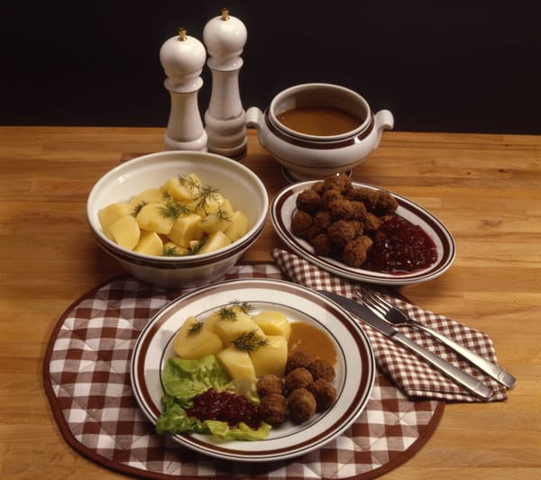 Köttbullar med tillbehör, upplagt på tallrikar och skålar på en rutig borsdtablett. 