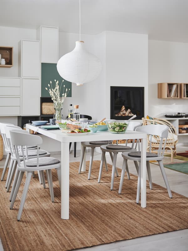 Kombinacija dnevne sobe i blagovaonice s kaminom, zidnim rješenjem za odlaganje i TINGBY blagovaonskim stolom s OMTÄNKSAM stolicama.