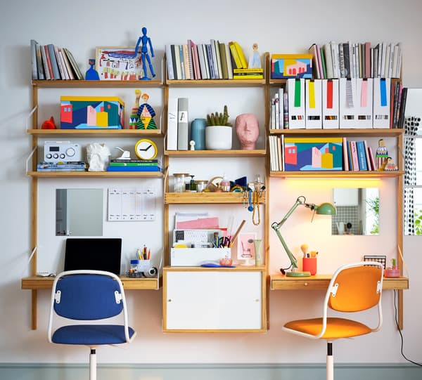Kombinasi ruang kerja lekap dinding SVALNÄS berwarna putih/dibuat daripada buluh dengan banyak buku, folder dan objek lain di atas para.