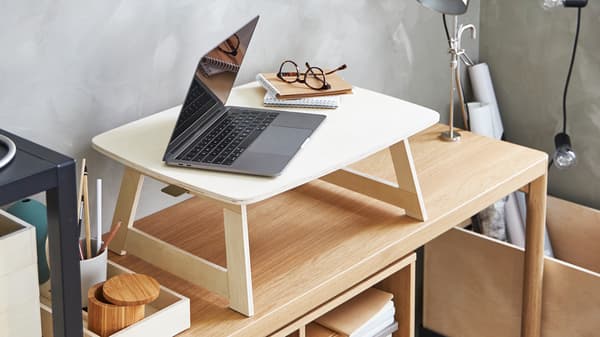 Komputer riba, pad nota dan cermin mata di atas dulang RÅVAROR papan lapis kayu birch yang terletak di atas meja konsol RÅVAROR venir kayu oak.