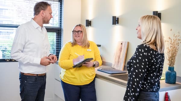 Konsultantka IKEA stoi wraz z parą klientów w kuchni w domu i notuje na tablecie.