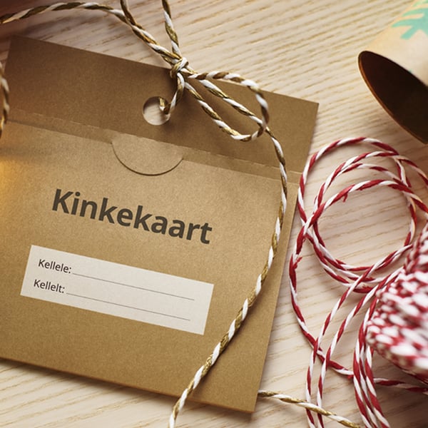 Коричневый конверт для подарочной карты с надписью «Kinkekaart» и декоративная бечевка на деревянном столе.