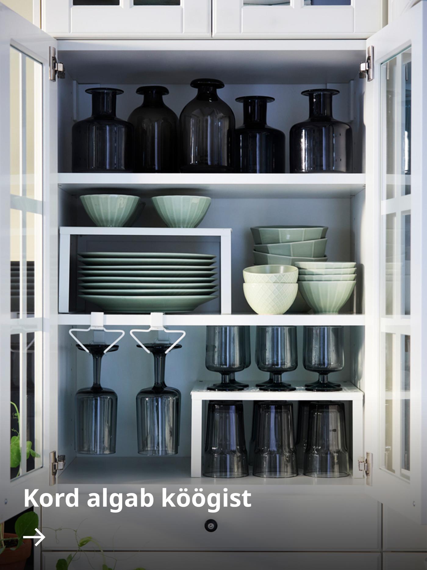 Korralikult paigutatud köögiseinakapp, mis on varustatud PÅLYCKE organiseerijatega ning sisaldab lauanõusid ja joogiklaase.