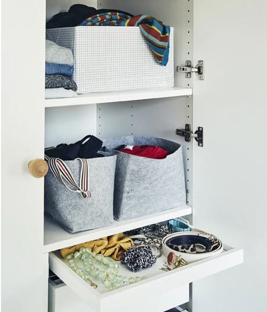 Kosarakkal, dobozokkal és és összehajtogatott ruhákkal teli fürdőszobapolcok.