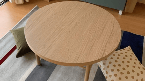 カーペットが敷かれ、円いローテーブルの周りにクッションが置かれている。