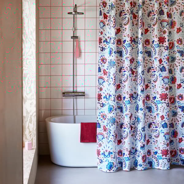 KRATTEN shower curtain featuring a traditional Scandinavian, floral pattern in many colours on a white background.