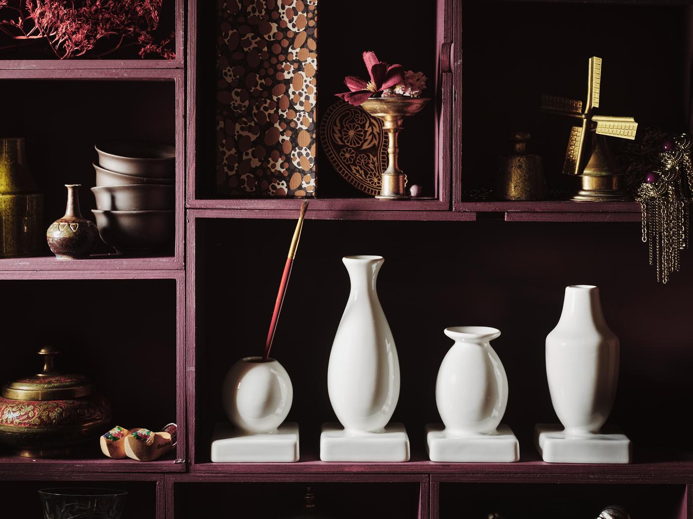 KRINGGÅ set of four vases in different shapes and sizes made in white-glazed stoneware placed in a cabinet of curiosities.
