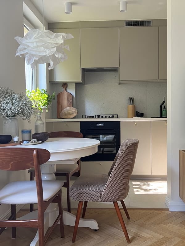 Kuchnia METOD z beżowymi frontami HAVSTORP. Na pierwszym planie okrągły stół z różnymi krzesłami.