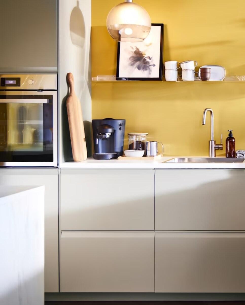 Kuhinja v svetlih barvah z rumeno steno.