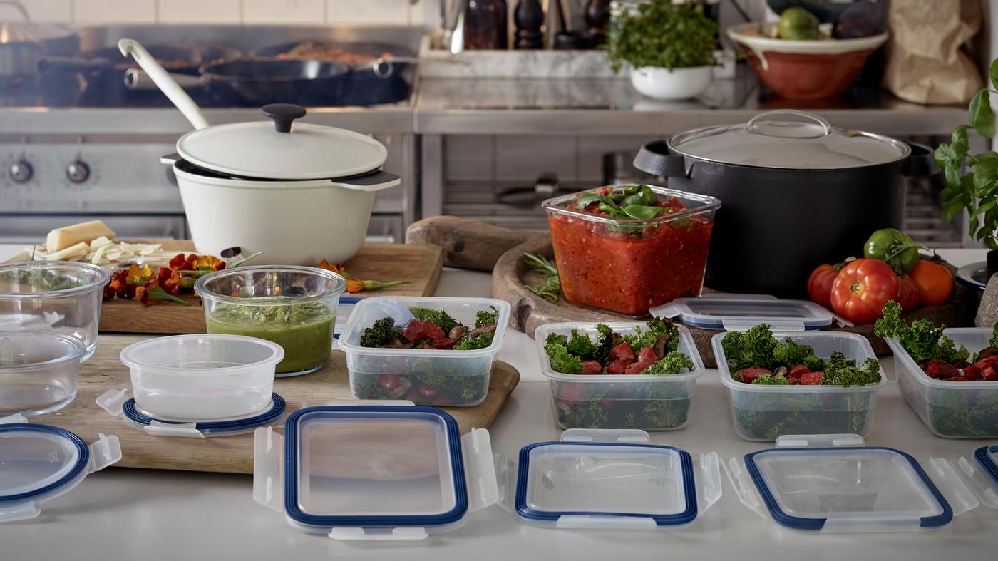 Kuhinjska radna klupa na kojoj se sprema hrana, s nekoliko posuda za hranu u različitim fazama pripreme.