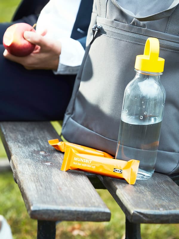 Kulacs, mellette pedig két MUNSBIT mogyorós szelet. A háttérben egy ember ül, kezében almát tartva.