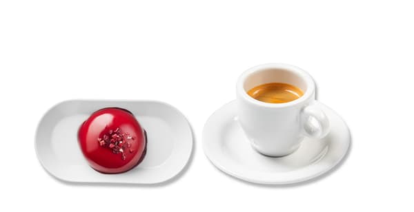 Kulatý malinový zákusek na oválném talířku a espresso v hrníčku
