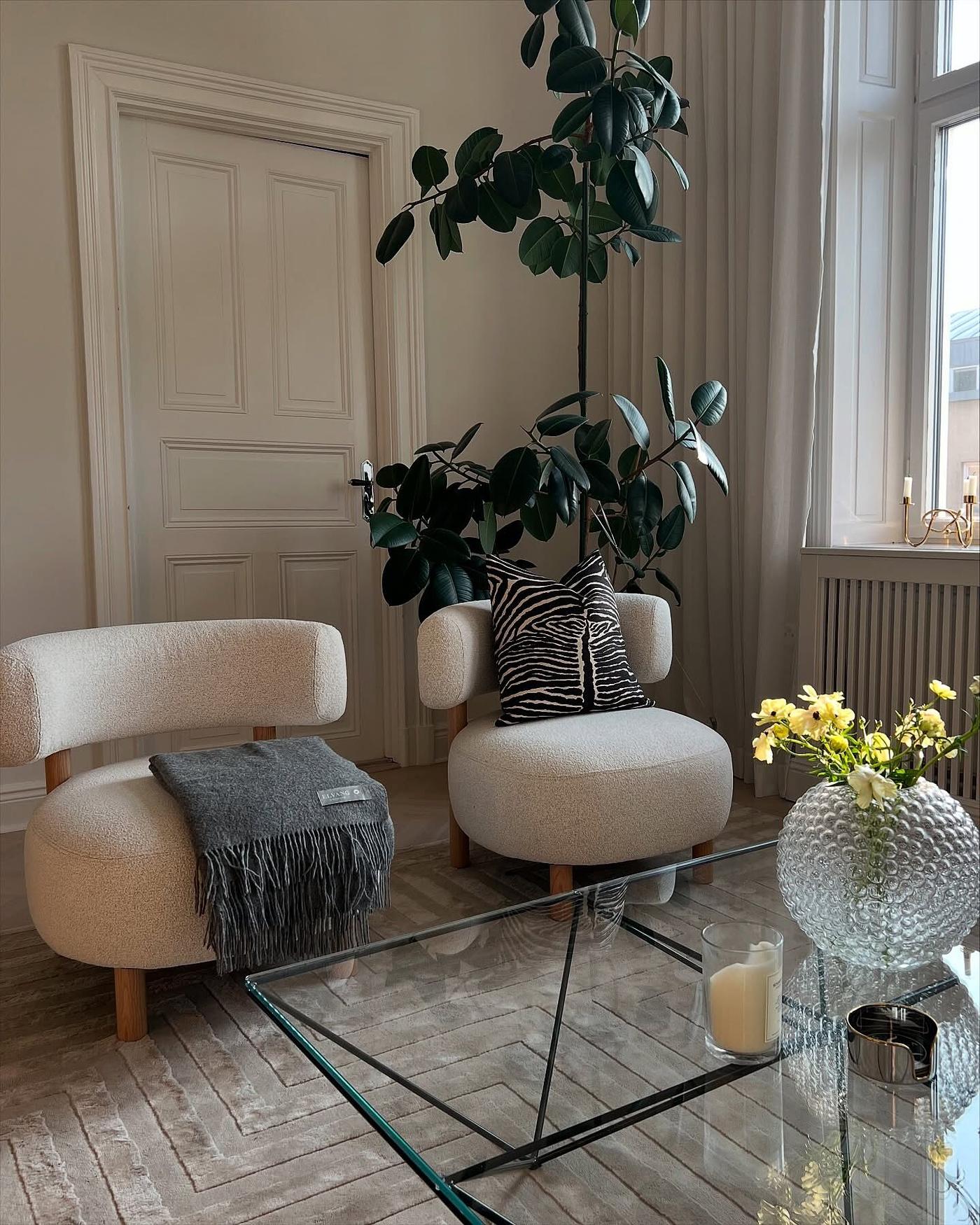 Kundbild från @lghbirka av två eleganta benvita STOCKHOLM 2025 boucléfåtöljer och ett soffbord i glas med en vas med gula blommor i ett stilrent vardagsrum.