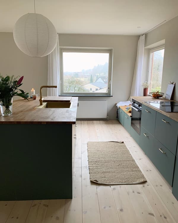 Kundbild på modernt kök med svarta skåp, vit vägg, hylla med köksprylar, inbyggd ugn och dekorationer.