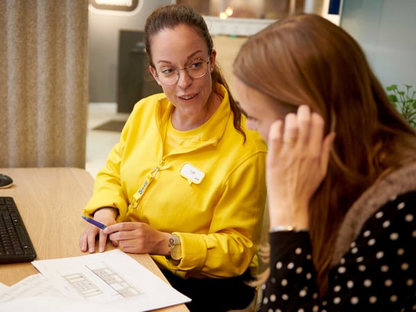 Kunden och IKEA-medarbetaren diskuterar ritningen vid bordet.