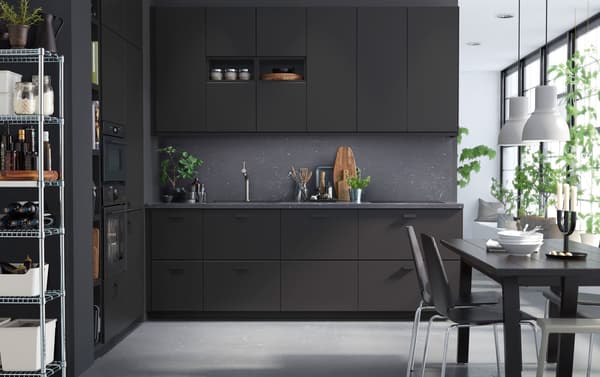 KUNGSBACKA keuken met kasten in antraciet, donkergrijze wanden en eettafel Licht straalt binnen vanuit een groot venster.