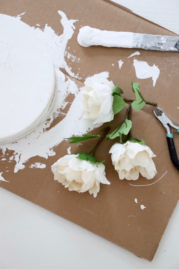 Kunstblumen liegen bereit, um auf der Korkplatten-Torte dekoriert zu werden.