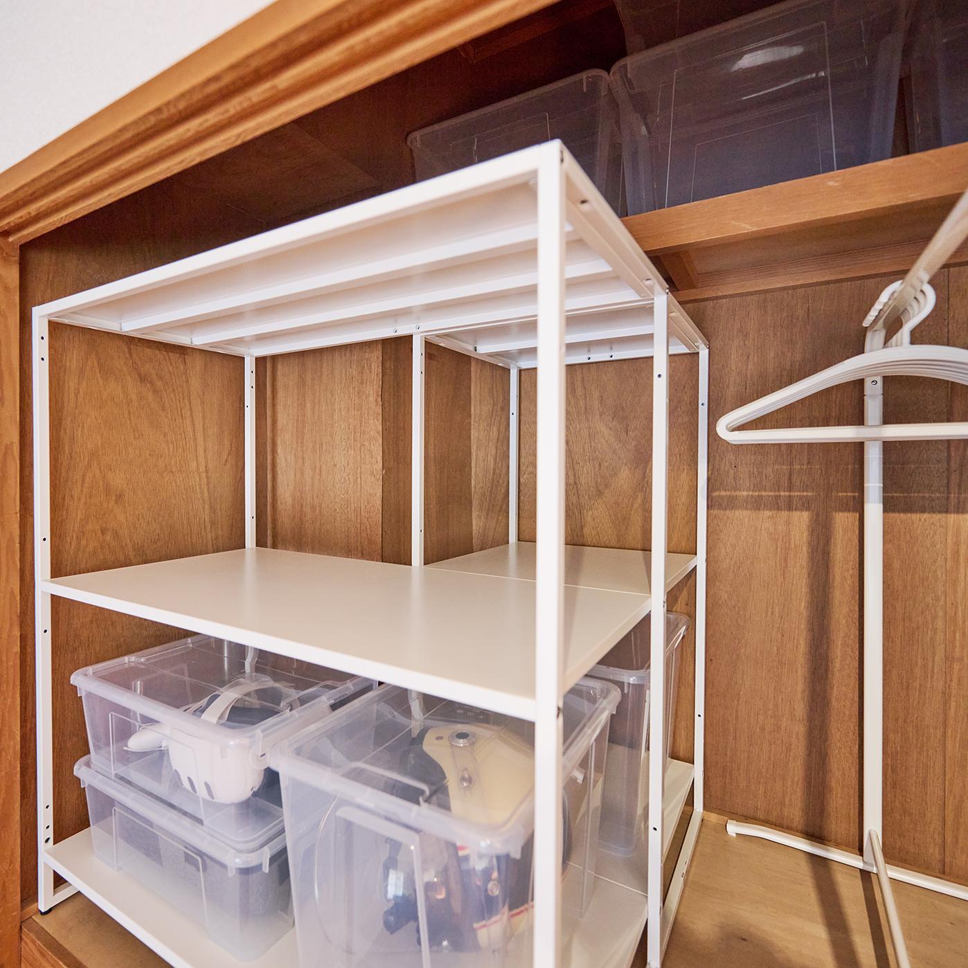 木製クローゼット内に、透明な収納ボックスを載せた白い金属製棚が設置されている。