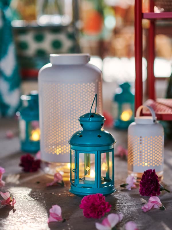 Kúsok neupravenej podlahy s lampášmi ROTERA a ÄDELHET, kvetmi a lupienkami rozhádzanými okolo.