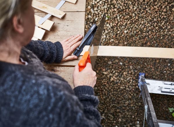 Kvinde saver en lamelbund over for at lave et gør-det-selv espalier.