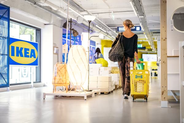 Kvinna går igenom butik med korg som släpas efter henne
