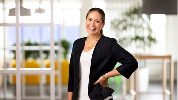 Kvinna i kontorsmiljö som ler mot kameran.