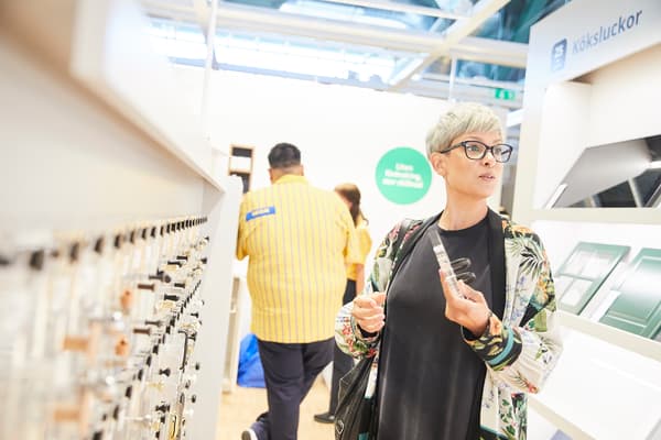 Kvinna med glasögon står i butik och håller upp ett varuprov