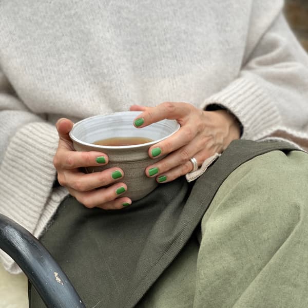 Kvinna som sittet i sitt växthus och njuter av en kopp kaffe. 