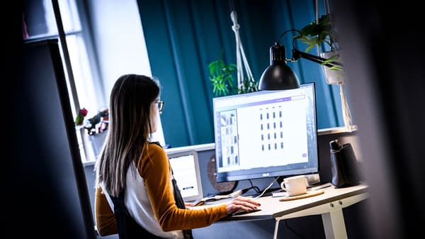 Kvinna står och jobbar vid ett ståskrivbord. 