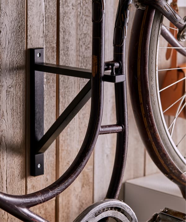 La bici sugli scaffali EKET è assicurata alla parete tramite la staffa EKBY dotata di pomello MÖLLARP.