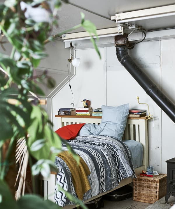 La camera di una house boat con un letto con biancheria colorata e libri appoggiati sul ripiano della testiera.