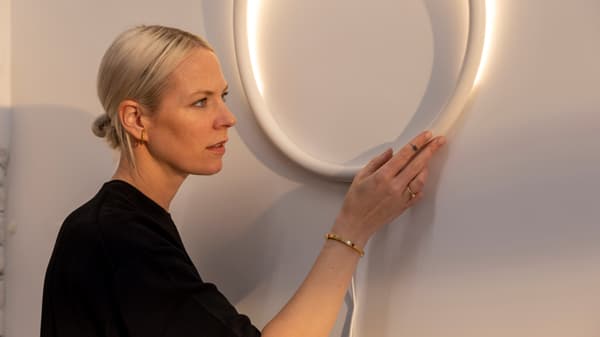 La designer Sabine Marcelis accroche un des éclairages de la collection circulaire VARMBLIXT à un mur.