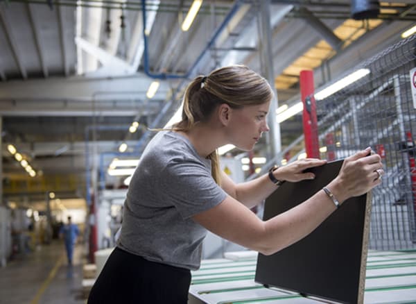 La développeuse produit Anna Granath tenant en main une façade de cuisine noire dans une usine.