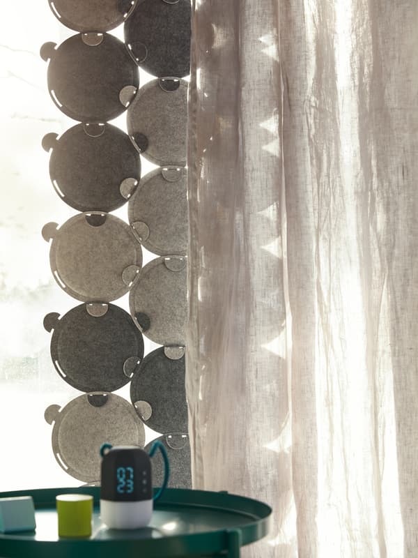 La luce filtra attraverso una finestra parzialmente coperta dai pannelli fonoassorbenti ODDLAUG e da una tenda opaca.