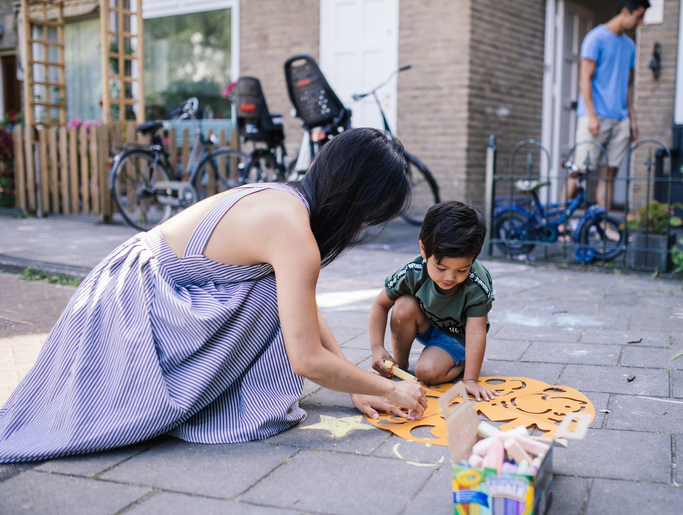 La mère et le jeune fils créent de l'art à la craie sur leur terrasse.