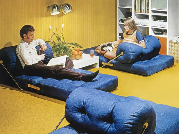 La photo de couverture du catalogue IKEA de 1973 montre un couple allongé sur deux fauteuils/relax TAJT dans une pièce à moquette jaune.