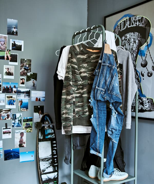 La stanza di un adolescente con pareti grigie, stand appendiabiti dal design industriale, stampe in stile graffiti e uno skateboard.