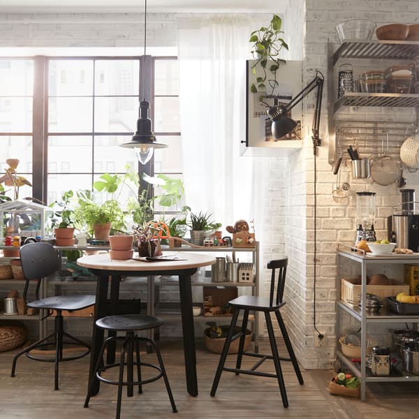 La table à manger IKEA GAMLARED a des pieds noirs et et un plateau rond en bois.