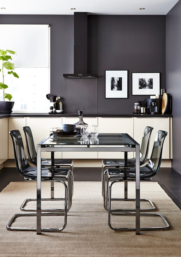 Laagpolig, taupe vloerkleed in een strakke, moderne keuken. Het vloerkleed ligt onder een eettafel met vier zwarte stoelen. Aan de wand hangen twee schilderijen.