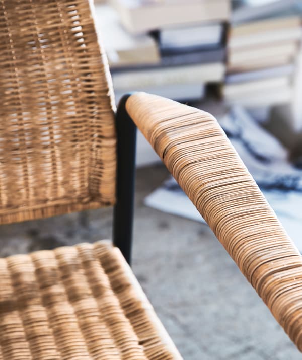 L'accoudoir et l’assise d’un fauteuil en rotin avec structure en métal.