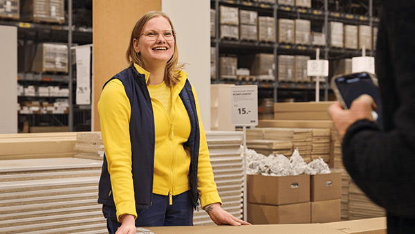 Lachende IKEA medewerker die opkijkt naar een klant die haar een vraag stelt.