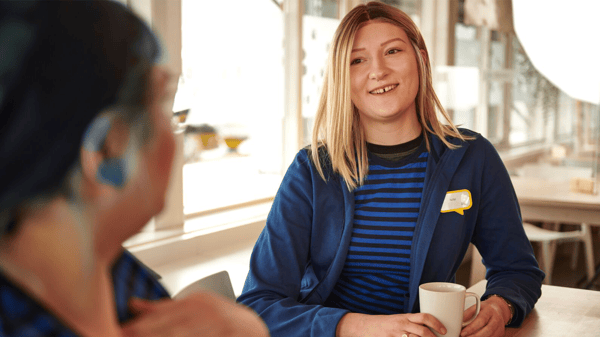Lachende IKEA medewerker is koffiepauze aan het houden met een collega.