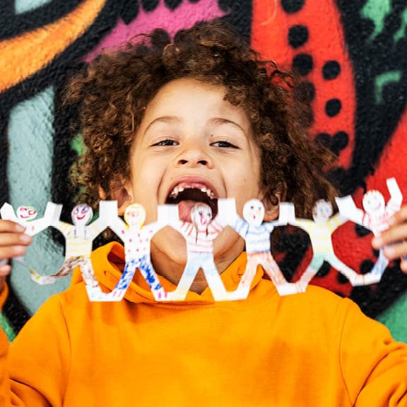 Lachendes Kind mit bunter Figurenkette aus Papier – Kreativspaß und Gemeinschaftssinn bei IKEA für Kinder.
