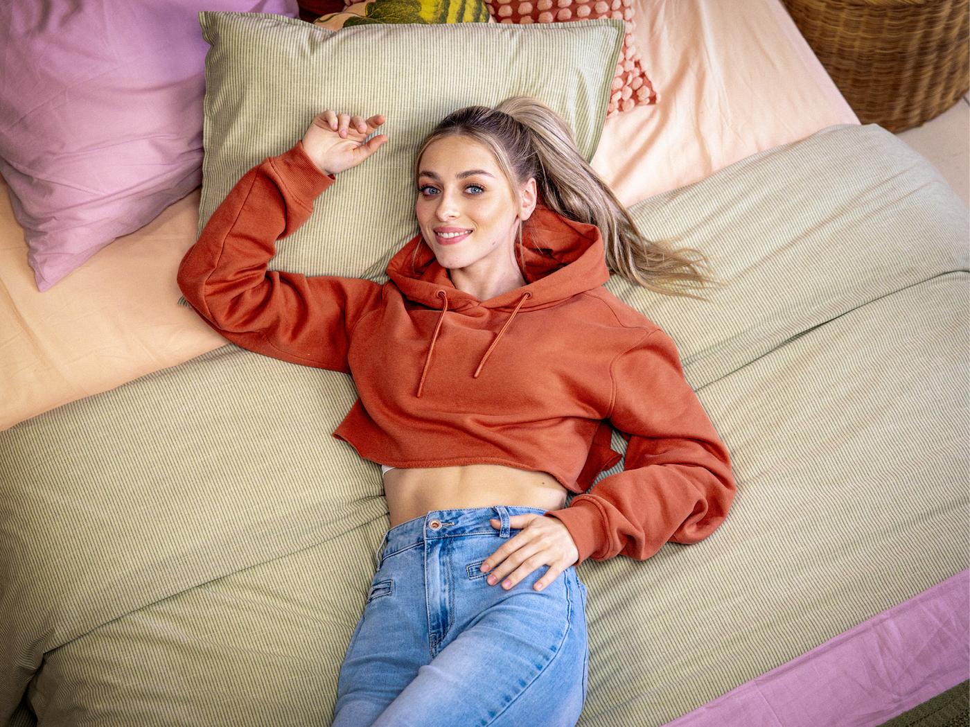 L’actrice Camille, qui joue le rôle de Milo, couchée sur un grand lit orné de linge de lit et de coussins colorés