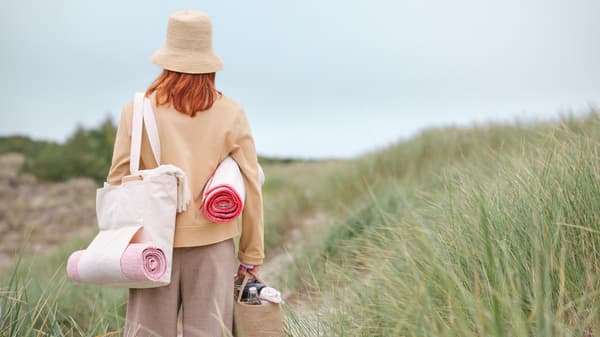 Lady walking on beach with VÅRDANDE collection items