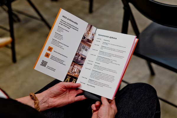 Lähivõte osaleja kätest, kes hoiab käes IKEA ärikliendikonverentsi programmi päevakavaga.